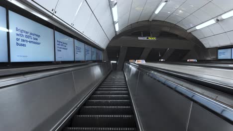 Empty-escalator-ascending-in-Tottenham-Court-Road-station,-London,-ads-lining-the-tunnel,-fisheye-lens