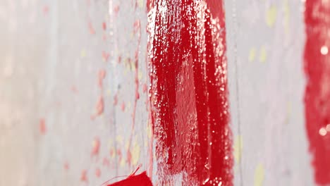 A-man-is-painting-a-wall-in-red-color-with-brush,close-up-shot,insert-shot