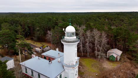 Der-Leuchtturm-Von-Uzava-An-Der-Ostseeküste-Steht-Hoch-Inmitten-Eines-Dichten-Grünen-Waldes,-über-Dem-Sich-Ein-Wolkiger-Himmel-Befindet