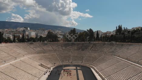 Cinematic-aerial-view-of-the-monumental-panathenaic-stadium-in-Athens-with-the-olympic-rings-in-the-center,-drone-footage