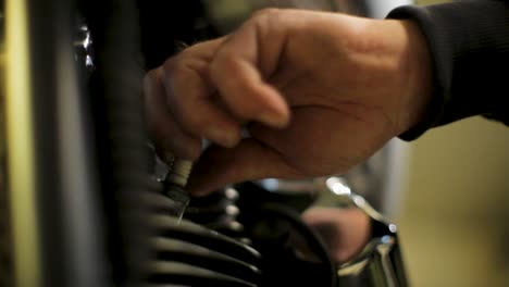 Close-up-of-a-hand-tightening-a-bolt-on-a-motorcycle,-focus-on-mechanical-work