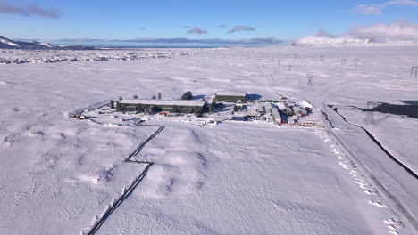 Instalación-Gigantesca-De-Captura-Directa-De-Aire-De-Climeworks-En-El-Paisaje-Nevado-De-Islandia,-Cielo-Azul,-Vista-Aérea