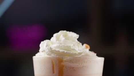 dropping-caramel-pieces-over-whipped-cream-side-view-milkshake