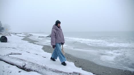 Hermosa-Mujer-Camina-Por-La-Playa-Nevada-En-Un-Frío-Día-De-Invierno-Slomo