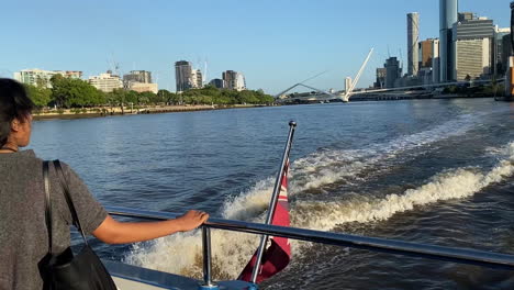 Female-admirers-the-view-from-rear-of-tourist-ferry,-Brisbane-City-Cat-with-city-in-the-background