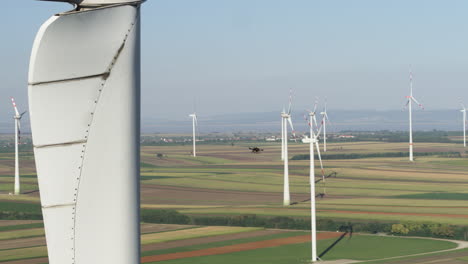 Amazing-scale-aerial-of-a-survey-drone-ascending-amongst-wind-turbines-in-an-energy-generation-plant
