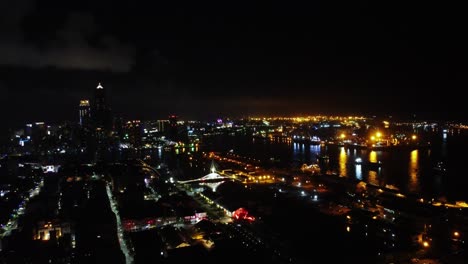 Nighttime-aerial-view-of-a-vibrant-cityscape-with-illuminated-streets-and-river