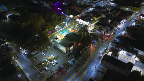 Hyperlapse-flight-over-Caribbean-City-at-night-with-traffic-on-people-playing-basketball-game-outdoors