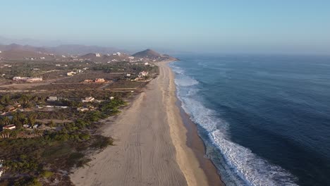 Baja-California-Sur-long-sandy-beach-protecting-lush-palm-trees-and-houses-from-Pacific-Ocean-waves