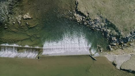 Una-Vista-Aérea-Hacia-Abajo-De-Una-Cascada-Artificial-Para-Un-Molino,-En-Un-Día-Soleado