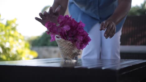 Mujer-De-Limpieza-Negra-Con-Decoración-Floral-Sobre-Una-Mesa-Al-Aire-Libre-Dentro-De-Un-Spa-De-Suite-De-Hotel-De-Lujo