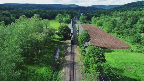 An-Aerial-View-of-a-Long-Steam-Passenger-Train-Approaching-on-a-Single-Track-Traveling-Thru-Green-Farmlands-on-a-Spring-Day