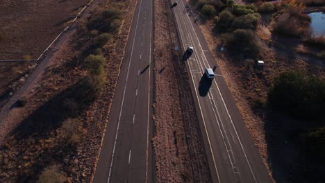 Vista-Aérea-Del-Tráfico-En-La-Ruta-Del-Estado-De-Arizona-Al-Atardecer,-Paisaje,-Autos-Y-Asfalto-Agrietado,-Revelando-Disparos-De-Drones