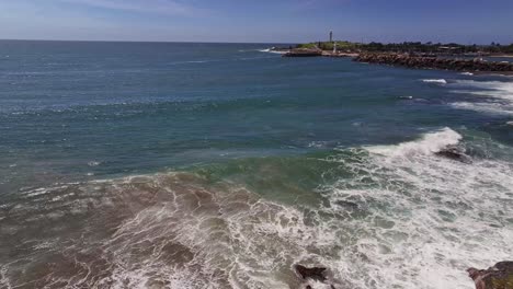 Antena-Que-Se-Eleva-Sobre-Rocas-Y-Olas-Y-Revela-Los-Faros-Y-El-Puerto-De-Wollongong-Más-Allá