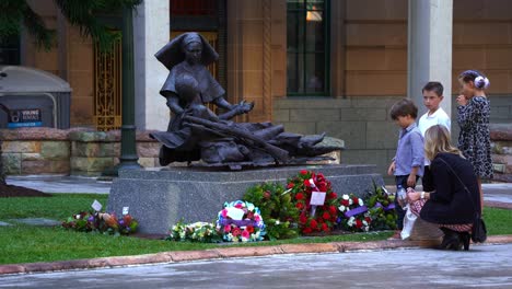 La-Joven-Generación-De-Australianos-Rinde-Homenaje-A-Quienes-Sirvieron,-De-Pie-Frente-A-La-Estatua-Conmemorativa-De-Las-Enfermeras-De-La-Segunda-Guerra-Mundial-Adornada-Con-Flores-Y-Coronas-En-La-Plaza-Anzac.