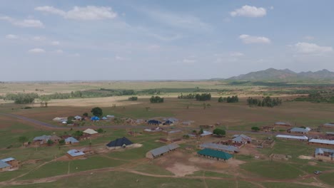 Aerial--Forward-panning-shot-of-isolated-settlement-on-vast-agricultural-expanse