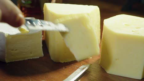Gouda,-Brie-and-Swiss-cheese-on-cutting-board-sliced-with-small-knife
