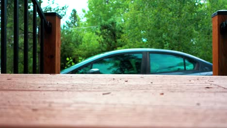 View-of-Parked-Car-from-a-Wooden-Deck-at-a-Cabin-in-the-Woods-with-a-Forest-and-Trees-in-the-Background