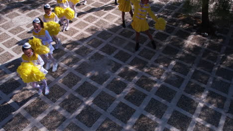 Aerial-View-of-Young-Majorette-Girls-in-Yellow-and-White-Uniforms-With-Pom-Poms