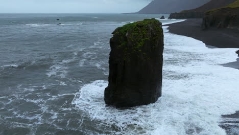 Foamy-Waves-Crashing-On-Sea-Stack-At-Laekjavik-Black-Sand-Beach-In-Iceland