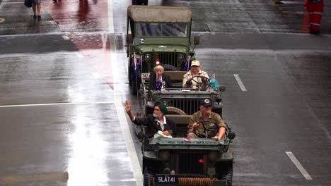Veterans-on-military-vehicle-driving-down-Adelaide-street,-waving-back-at-the-cheering-crowds-during-Anzac-day-parade