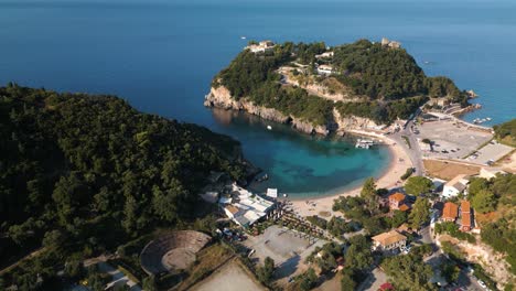 Schnelle-Luftaufnahmen-Zeigen-Eine-Geschützte-Sandbucht-Und-Einen-Strand-Mit-Booten-Am-Dock-Und-Menschen,-Die-Sich-Auf-Korfu,-Griechenland-Entspannen