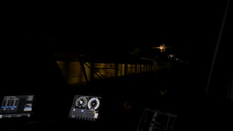 Train-conductor's-view-of-a-bustling-station-platform-at-night,-control-panel-in-foreground