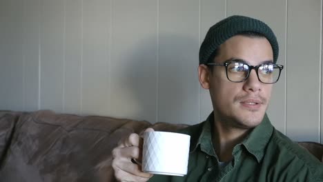 Young-Man-with-Beanie-and-Glasses-Drinks-Coffee-out-of-a-Mug-CU-STATIC
