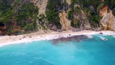 Panorámica-Con-Drones-Frente-A-Las-Calizas-Rocosas-Detrás-De-La-Aislada-Playa-De-Petanoi,-Ubicada-En-La-Isla-De-Cefalonia,-En-La-Costa-Occidental-De-Grecia.