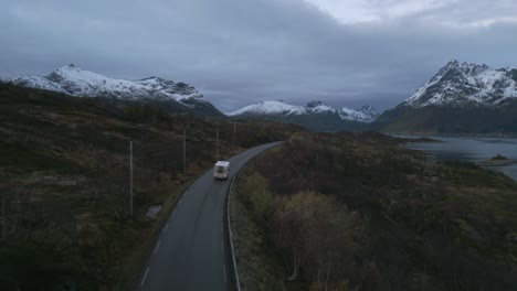 Twilight-descends-on-Lofoten's-road-with-a-camper-van-amidst-snowy-peaks