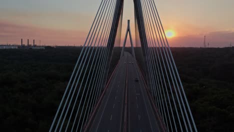 Aerial-flying-between-cables-of-Mauricio-Baez-Bridge-at-sunset,-Dominican-Republic