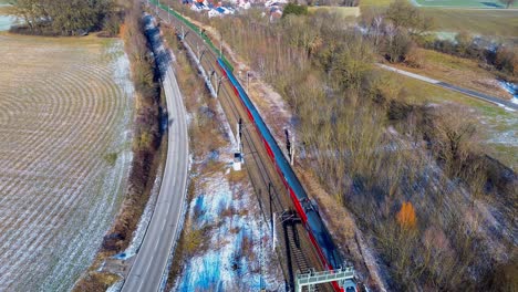 Vibrant-Red-Train-Traversing-Alongside-Frosted-Fields