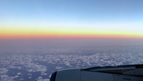 Sonnenuntergangsfarben-über-Den-Wolken-Aus-Einem-Flugzeugfenster,-Sanfter-Pastellfarbener-Himmel,-Ruhige-Reiseszene,-Blick-Aus-Großer-Höhe