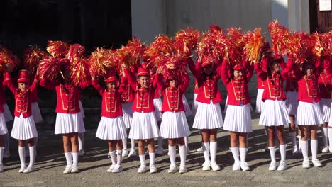 Young-Girls-Majorettes-in-Red-Uniforms-Waving-With-Pom-Poms