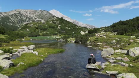Woman-sits-on-Rock-at-Water-River-in-Pirin-Mountains-National-Park,-Bulgaria
