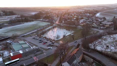 Panoramic-View-Of-Snowy-Landscape-And-People-Skating-On-Frozen-Lake---Drone-Shot