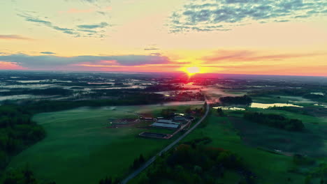 Hermoso-Y-Exuberante-Paisaje-Rural-Verde-En-Condiciones-De-Niebla,-Amanecer-Rojo-Matutino,-Toma-Aérea-De-Camión