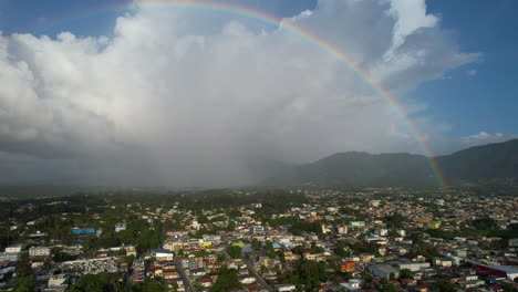 Aerial-establishing-shot-of-Jarabacoa-City-with-beautiful-rainbow-at-sky
