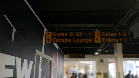 Busy-airport-sign-interior-with-gates-toilets-and-lounge-bustling-with-travellers