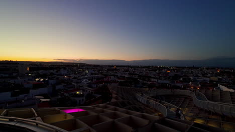 El-Crepúsculo-Desciende-Sobre-Sevilla-Con-Las-Luces-De-La-Ciudad-Parpadeando,-Capturando-La-Transición-Del-Día-A-La-Noche,-Vista-Panorámica
