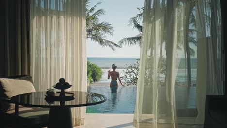 Elegante-Frau-Trinkt-Wein-Am-Rand-Des-Infinity-Pools-Und-Blickt-Aufs-Meer-Auf-Bali