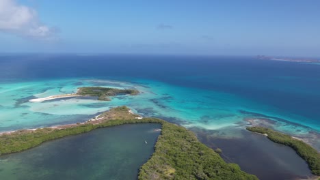 The-mangrove-forest-and-lagoon-in-los-roques,-venezuela,-vibrant-blue-waters-embracing-green-islands,-aerial-view