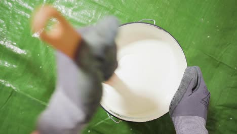 Man-mixing-white-paint-in-a-bucket-with-a-wooden-stick