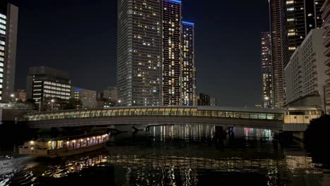 Nachtstadtbild-Mit-Beleuchteten-Gebäuden-Und-Einer-Brücke,-Die-Sich-über-Dem-Wasser-Spiegelt,-Ruhige-Stadtszene