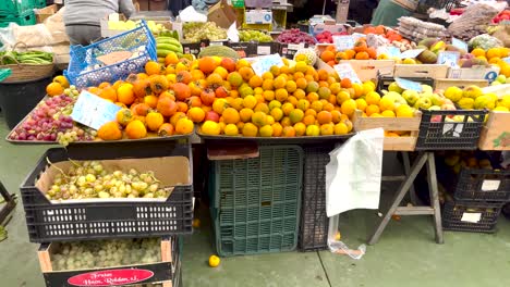 Market-Worker-Arranging-Produce-and-Customer-Picking-Fruit-in-Lisbon,-Portugal