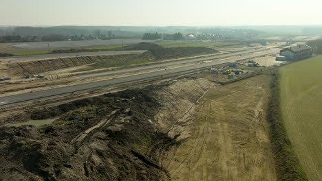 Aerial-view-of-an-extensive-highway-construction-site-with-dirt-mounds-and-equipment