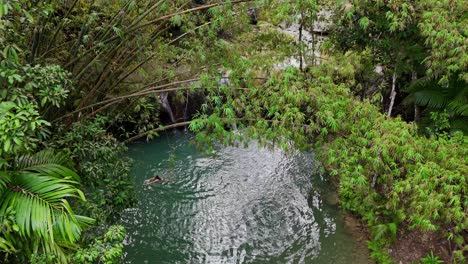 Drohnenaufnahmen-Eines-Wasserfalls-Mit-Einem-Schwimmer-Auf-Der-Insel-Siquijor-Auf-Den-Philippinen