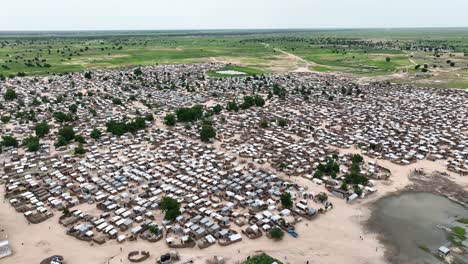 Static-high-angle-shot-of-makeshift-Nigerian-refugee-town-with-oasis-near-meadow