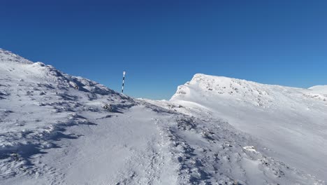 Schneebedeckte-Hänge-Von-Bucegi-Mit-Iezer-Papusa-Und-Piatra-Craiului-In-Der-Ferne,-Blauer-Himmel