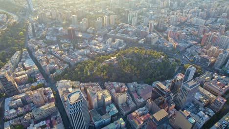Aerial-drone-top-down-Santa-Lucía-hill-Santiago-de-chile-city-town-panoramic-sun-shining-above-south-American-capital,-buildings-streets-urban-park-at-daylight